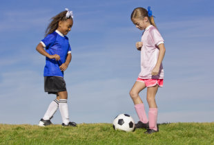 Two young girls on youth soccer teams playing against each other