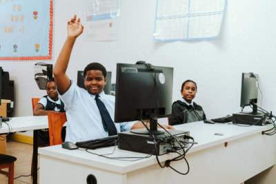 boy student in a computer lab raising his hand