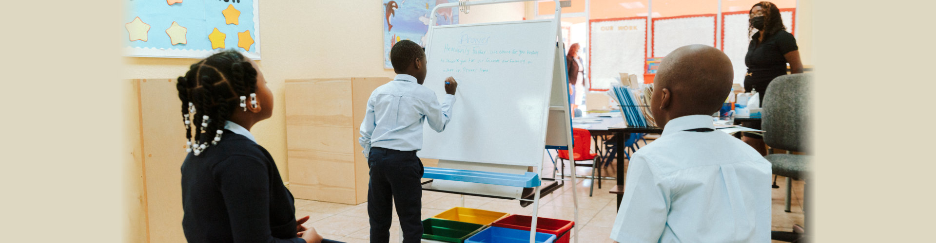 student writing in a whiteboard with teacher and other students