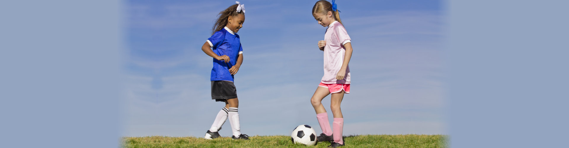 Two young girls on youth soccer teams playing against each other